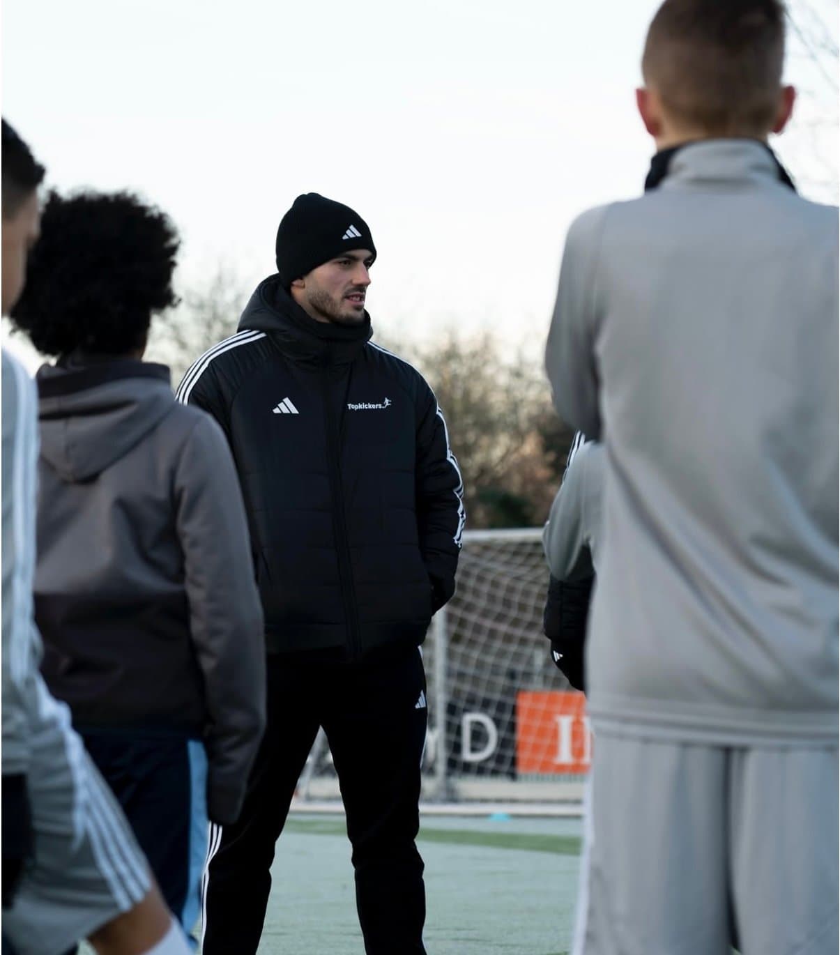 Trainer in gesprek met een groep spelers op het veld